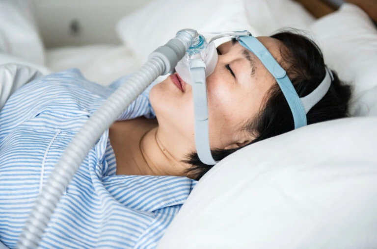 A woman sleeping in bed with an oxygen mask.