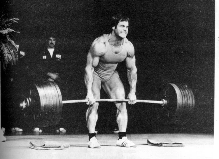 An old photo of a man lifting a barbell.