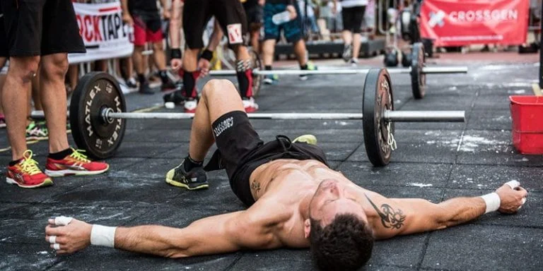 A man laying on the ground at a crossfit competition.