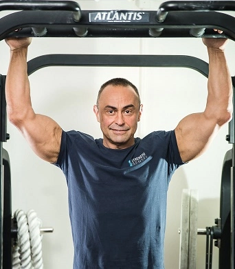 A man in a gym holding a pull up bar.