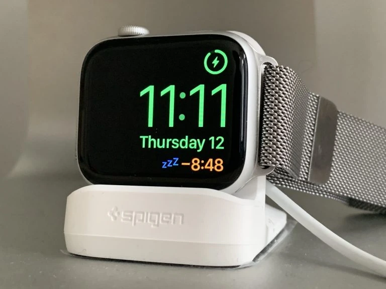 A white apple watch is sitting on a stand.