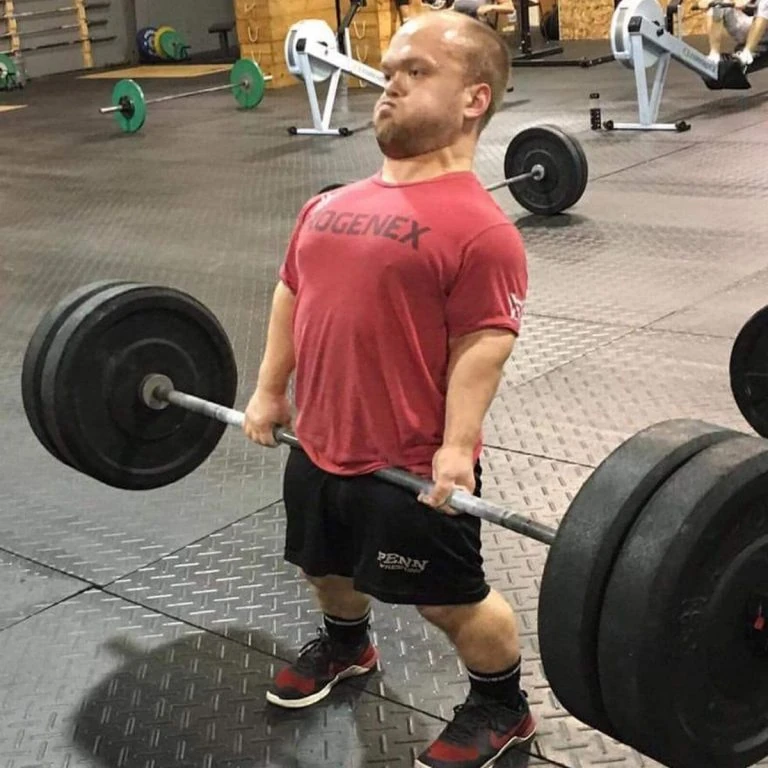 A man lifting a barbell in a gym.