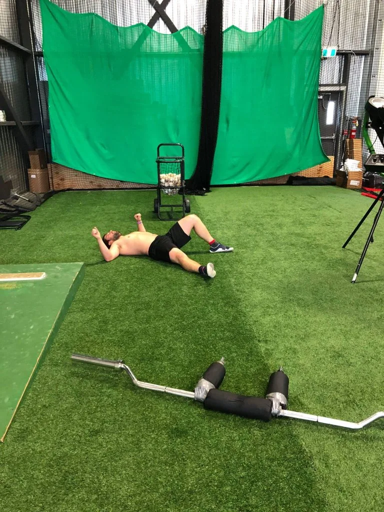 A man laying on the ground in front of a green screen.