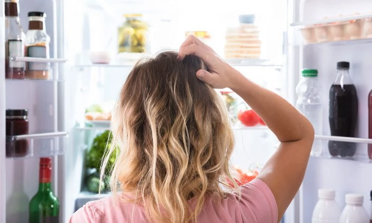 A woman looking into an open refrigerator.