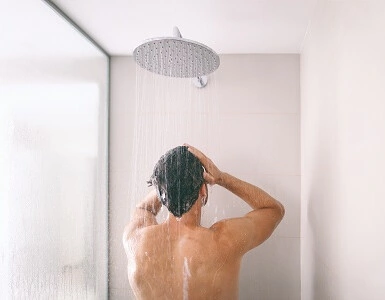 A man is taking a shower in a bathroom.