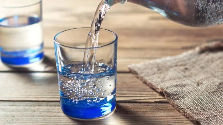 Water being poured into a glass on a wooden table.