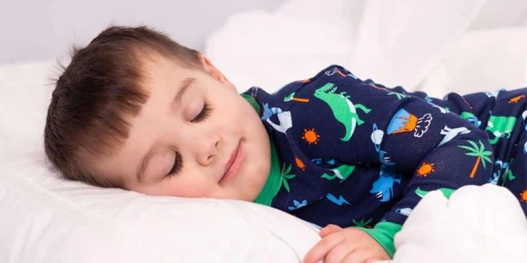 A young boy sleeping in a blue pajama.