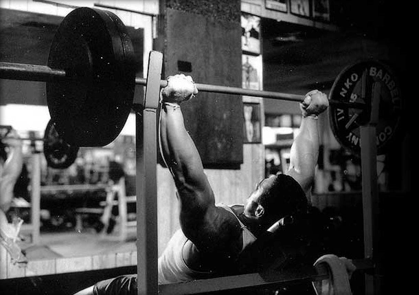 A man lifting a barbell in a gym.