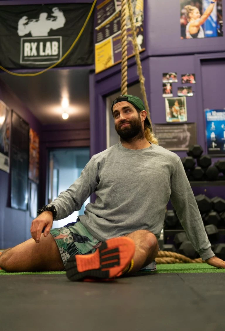 A man sitting on the floor in a gym.