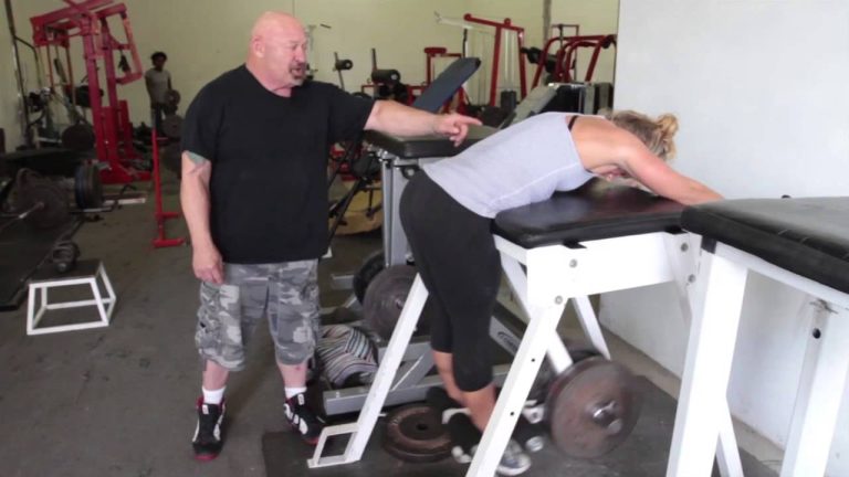 A man and a woman working out in a gym.