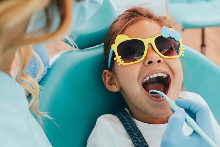 A young girl is getting her teeth cleaned by a dentist.