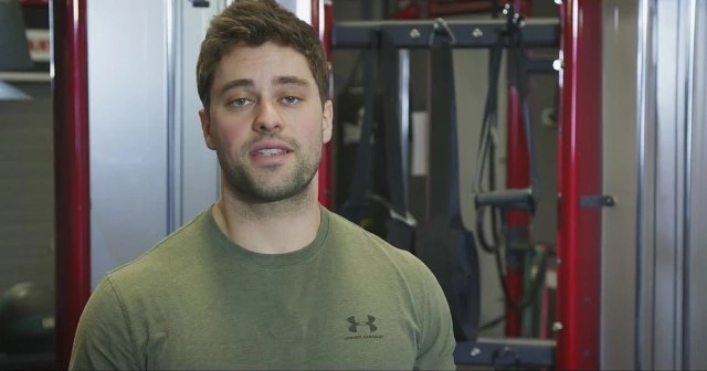 A man in a green shirt standing in front of a gym.