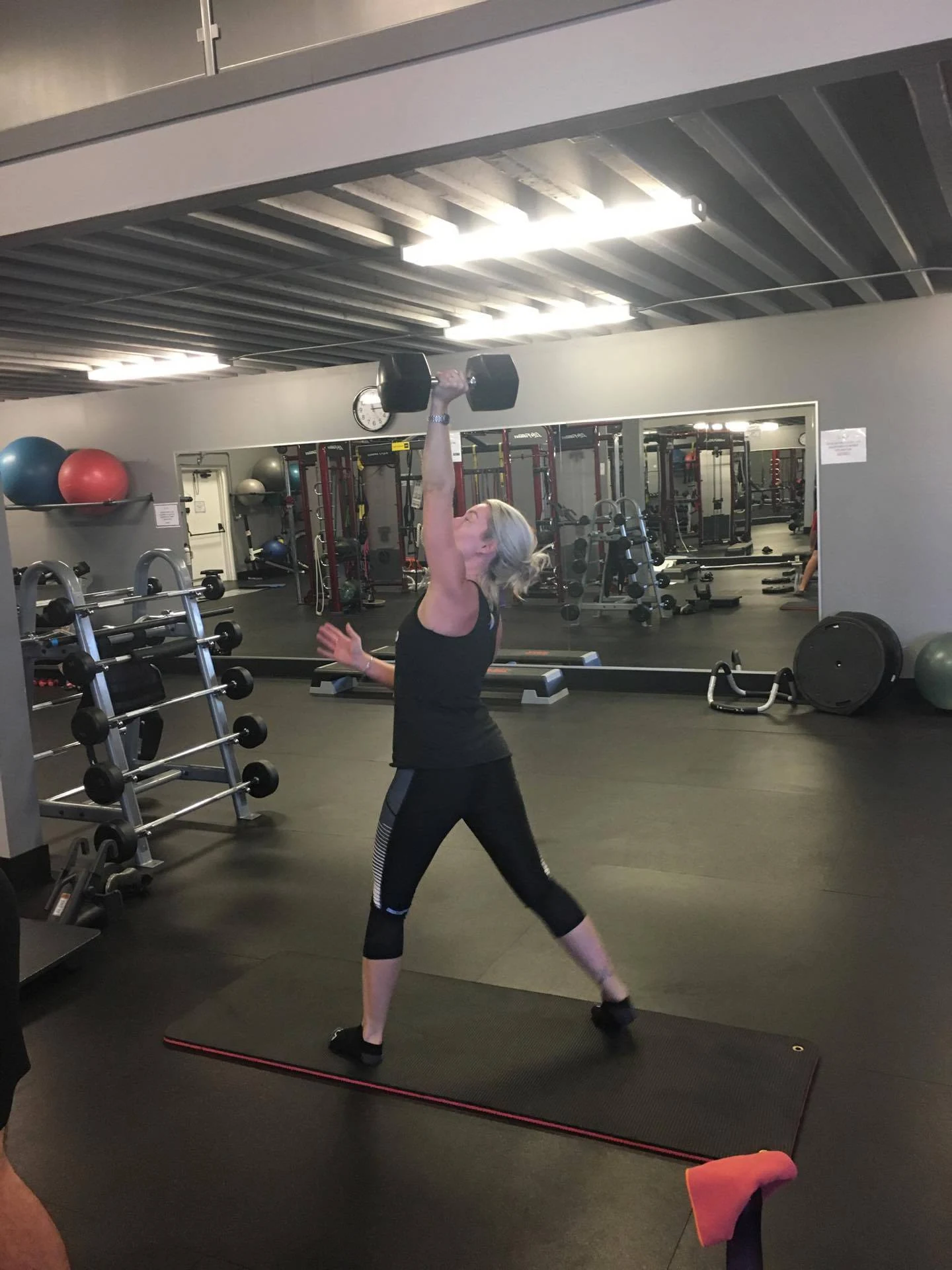 A woman lifting a dumbbell in a gym.