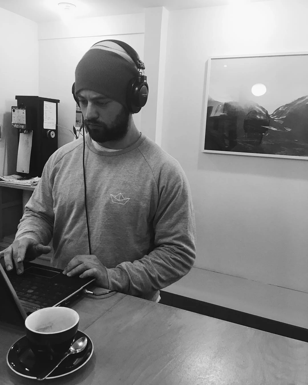 A man is working on a laptop with headphones on.