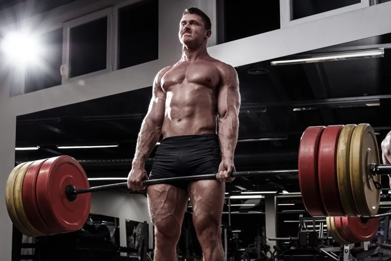 A man lifting a barbell in a gym.