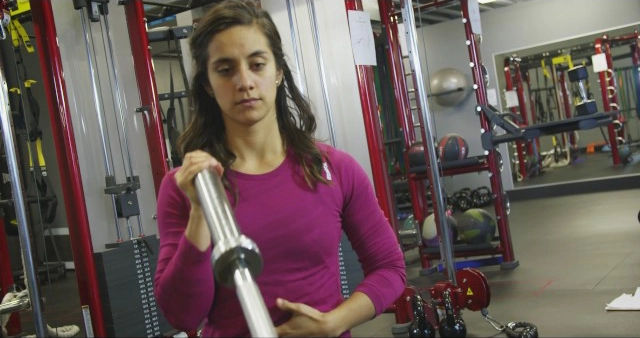 A woman holding a barbell in a gym.