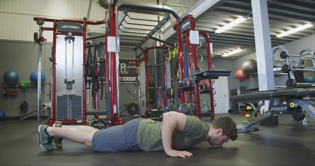 A man doing a push up in a gym.