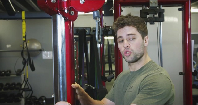 A man is standing in front of a gym machine.